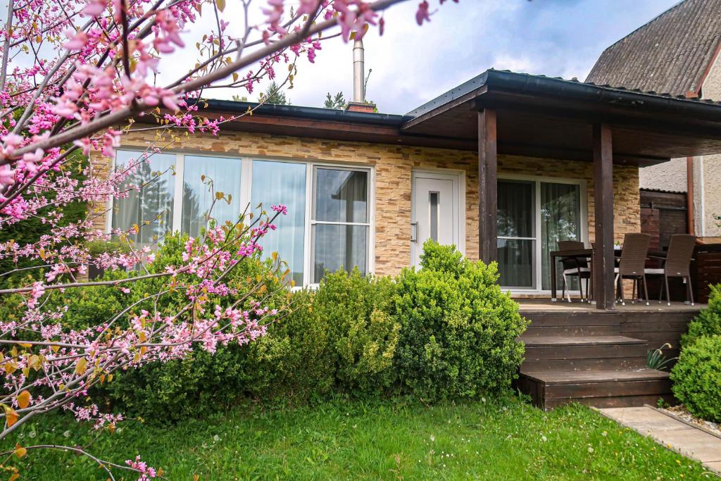 a house with a porch and a deck with pink flowers at Sweet Home in Příchovice