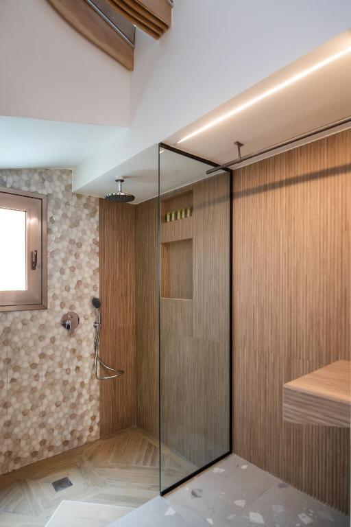 W łazience znajduje się prysznic ze szklanymi drzwiami. w obiekcie Aelia Suites w mieście Áyios Pétros