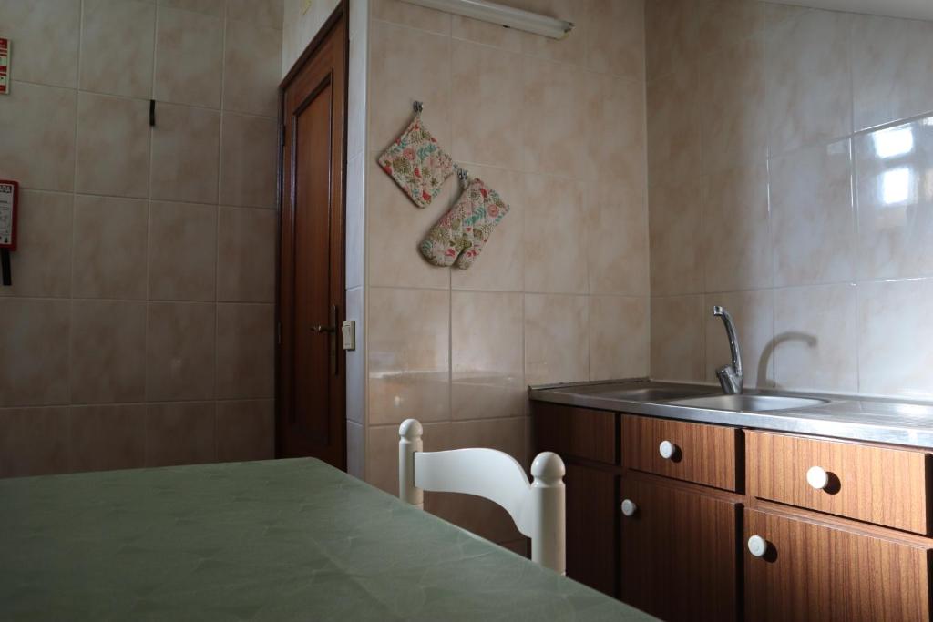 eine Küche mit einer Spüle, einem Tisch und einer Theke in der Unterkunft AL Vila Lina in São Pedro do Sul