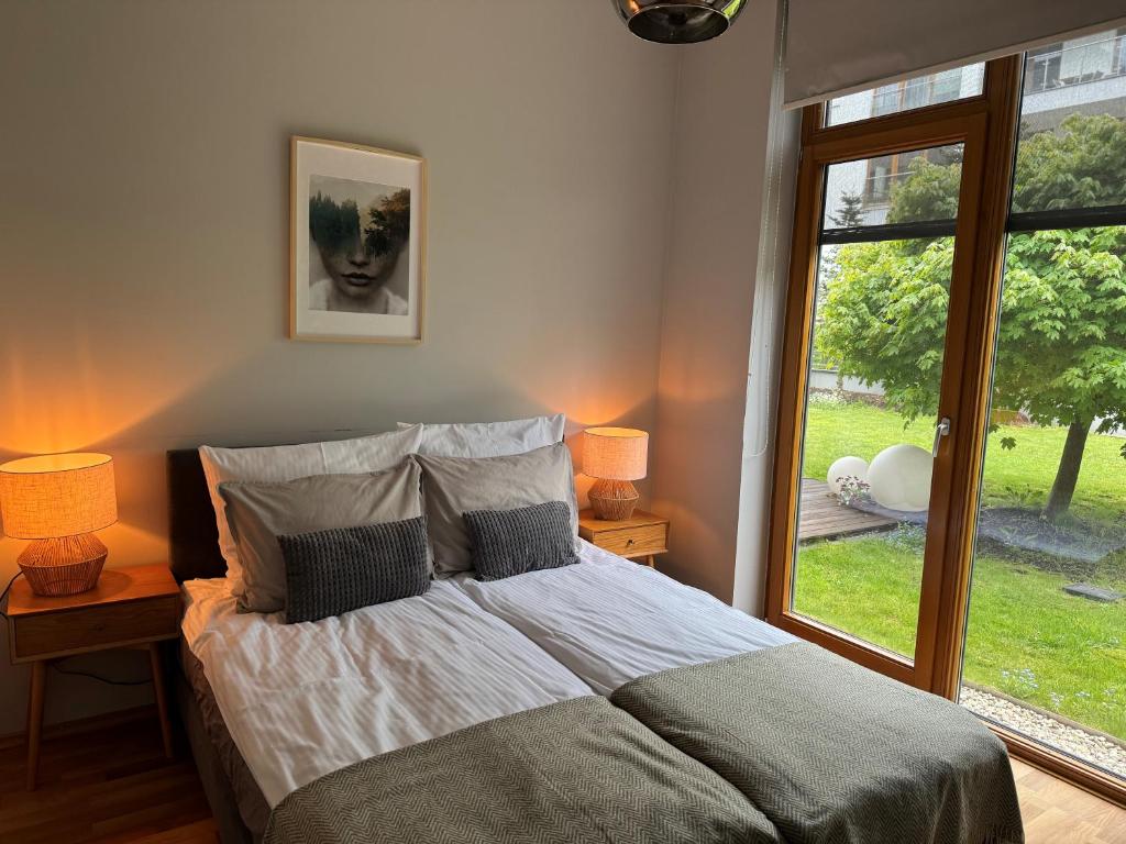 ein Schlafzimmer mit einem Bett mit zwei Lampen und einem Fenster in der Unterkunft WILANOWSKA apartment & garden in Warschau
