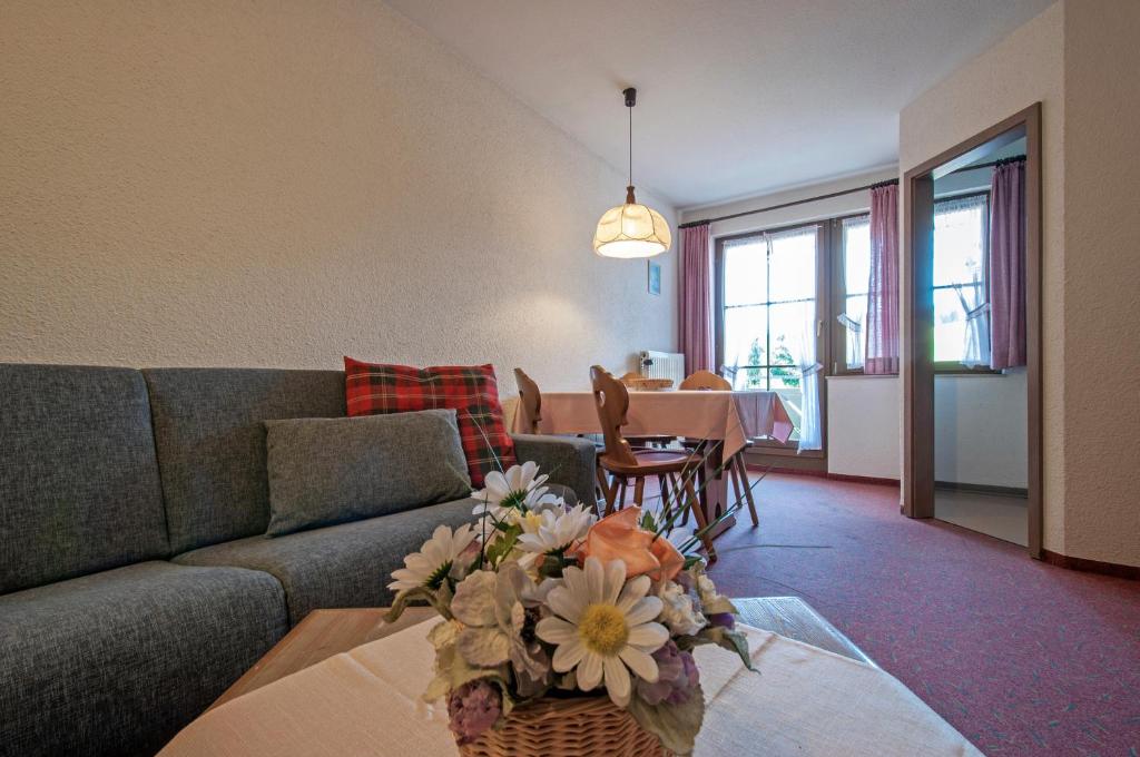 un soggiorno con divano e tavolo con fiori di Apartment 05 - Ferienresidenz Roseneck, 2 Schlafzimmer, mit Schwimmbad in Todtnauberg bei Feldberg a Todtnauberg