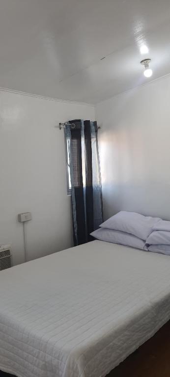 uma cama branca num quarto com uma janela em Caryolba hometel em Calapan