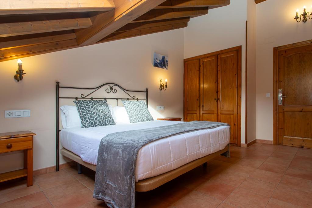 Un dormitorio con una cama grande en una habitación con techos de madera. en Hotel Naranjo De Bulnes, en Arenas de Cabrales