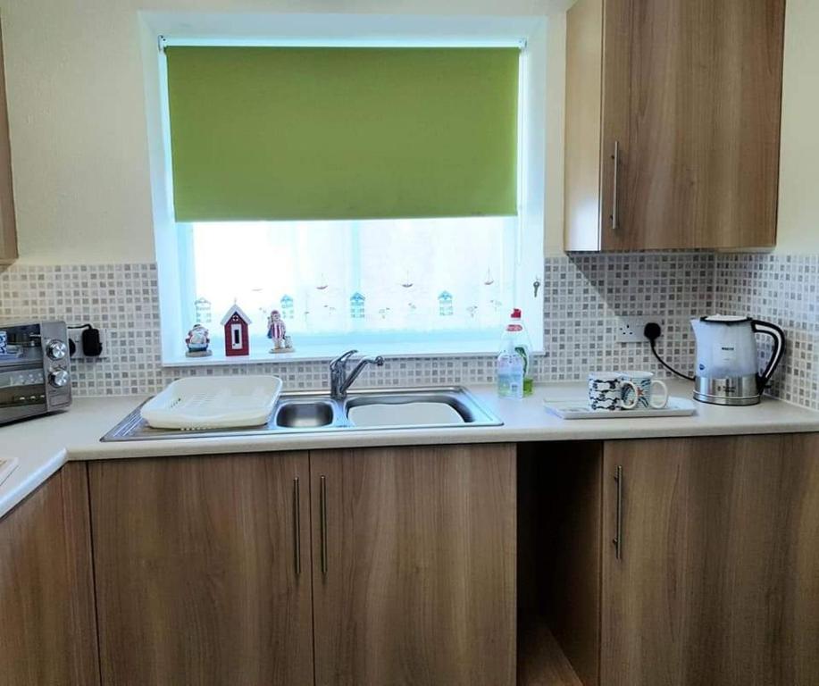 a kitchen counter with a sink and a window at Rogie's place in Woolacombe