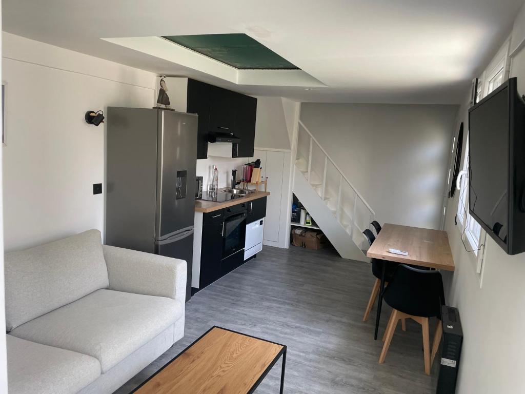 a living room with a white couch and a kitchen at Joli duplex in Colombes