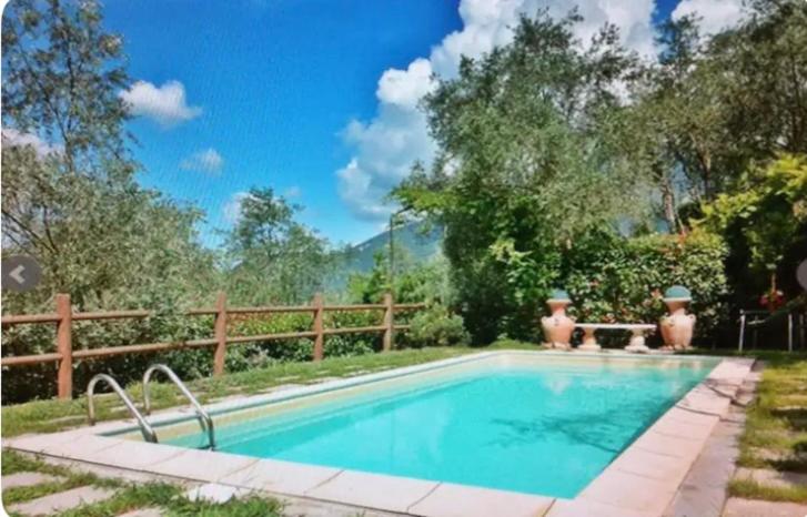 una piscina en un patio con una valla de madera en Villa Oscar con piscina e palestra, en Camaiore