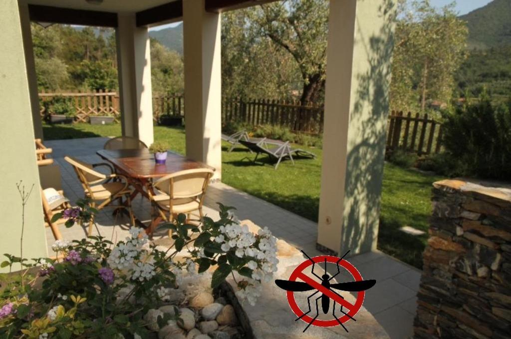 un patio con mesa, sillas y flores en Terre Di Garlenda, en Garlenda