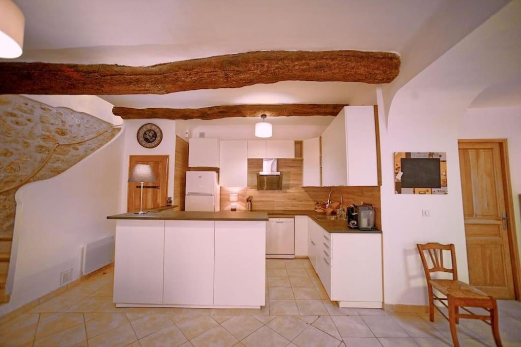 duża kuchnia z białymi szafkami i stołem w obiekcie Maison de village Les amandiers w mieście Baudinard