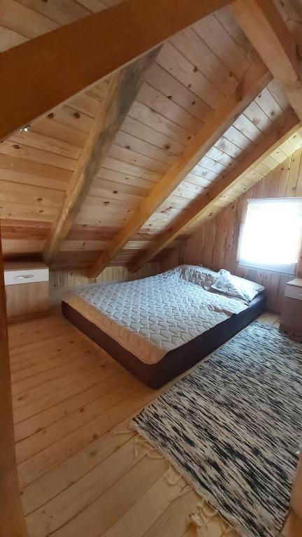 Cama grande en habitación de madera con alfombra en Vikendica Monte, en Ledinci