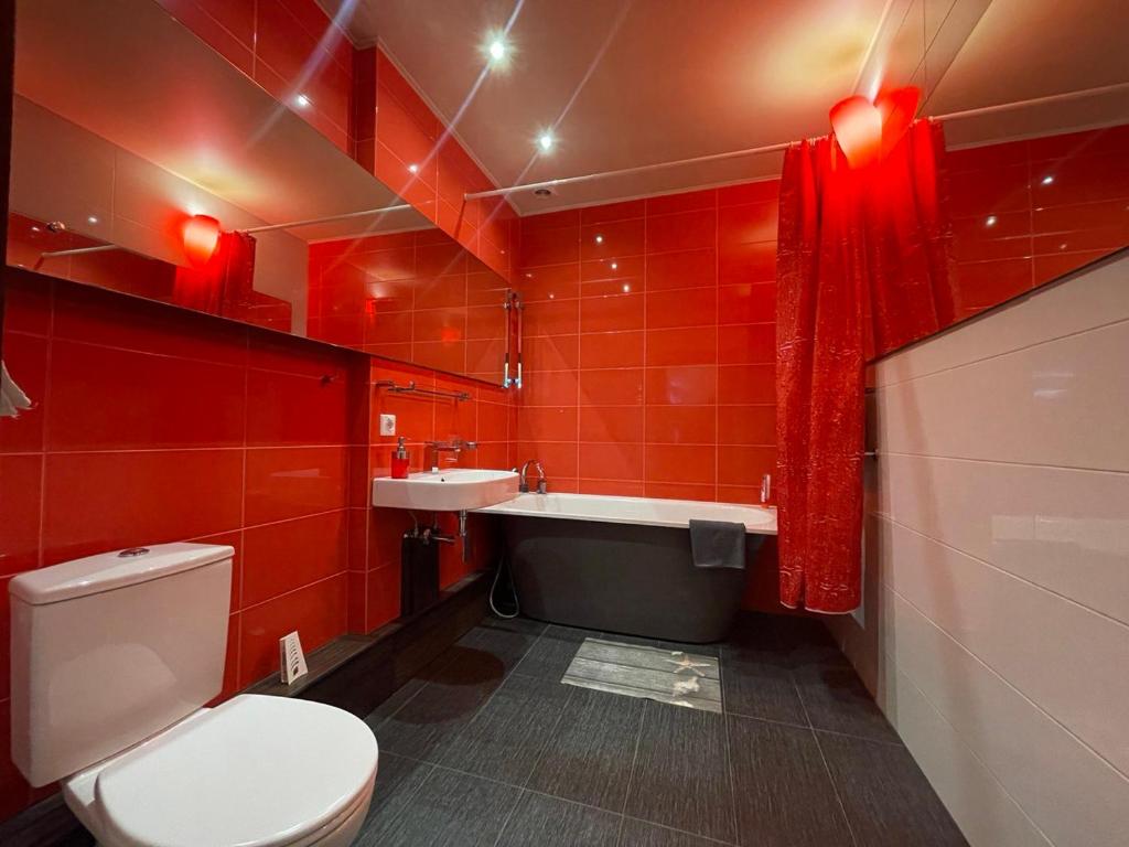 La salle de bains rouge est pourvue de toilettes et d'un lavabo. dans l'établissement Meza House Apartment, à Jurmala