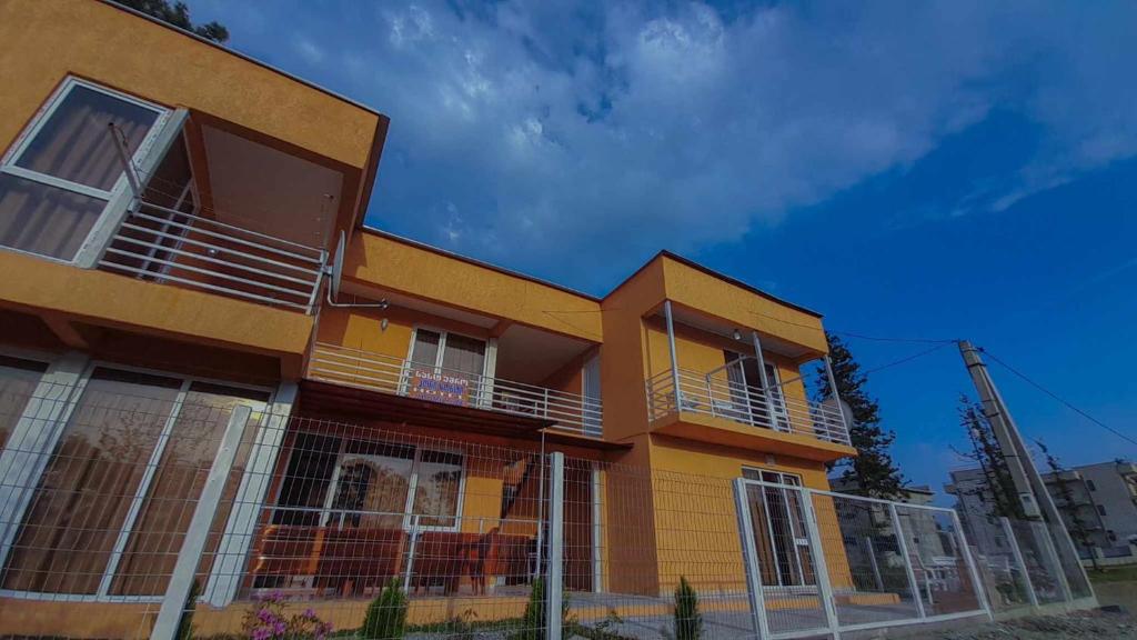 a yellow house with a fence in front of it at Horizon in Ureki