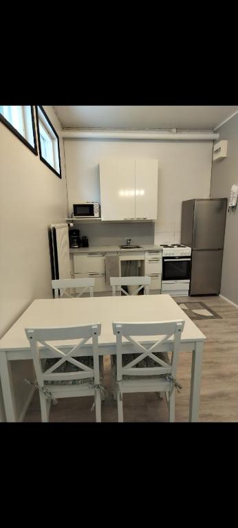 une cuisine avec une table blanche et deux chaises dans l'établissement Your loft, à Seinäjoki
