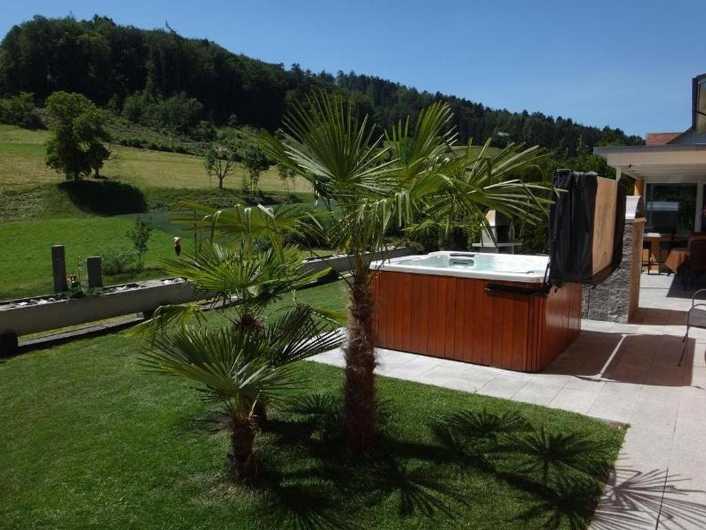 a hot tub with a palm tree in a yard at Residenza San Remy in Unterkulm