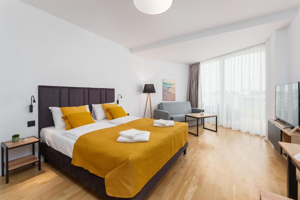 a bedroom with a large bed and a television at Apartament Prywatny Seaside Park 649 in Kołobrzeg