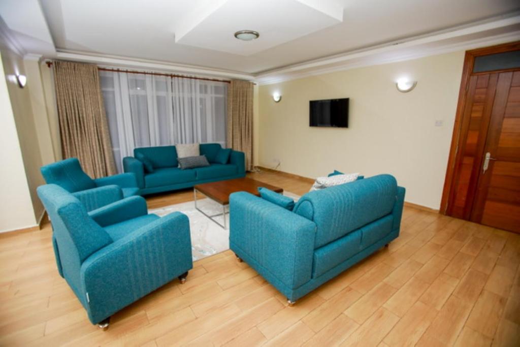 a living room with two blue couches and a television at WHITE LOTUS EXECUTIVE APARTMENT in Meru
