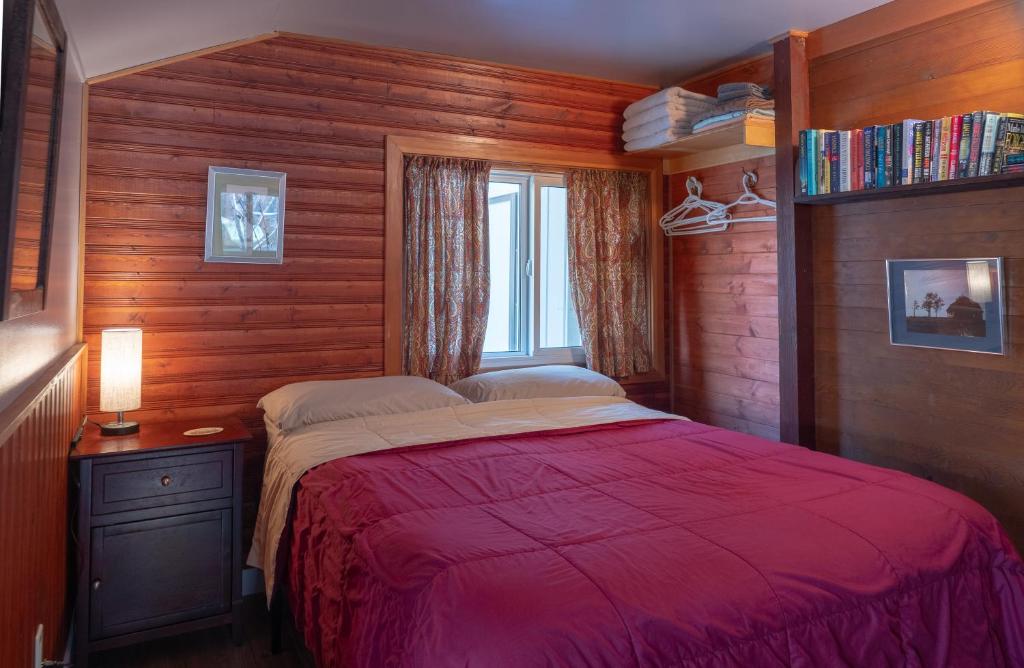 a bedroom with a red bed and a window at Hillside Bungalows in Banff