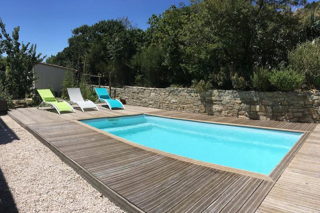une piscine avec des chaises et une terrasse en bois dans l'établissement Villa avec piscine dans la garrigue entre Narbonne et Méditerranée, à Armissan