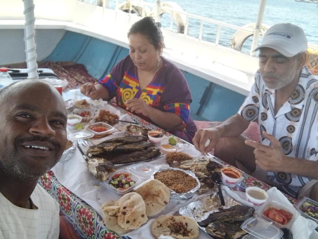 a group of people sitting around a table of food at Ozzy Tourism in Aswan