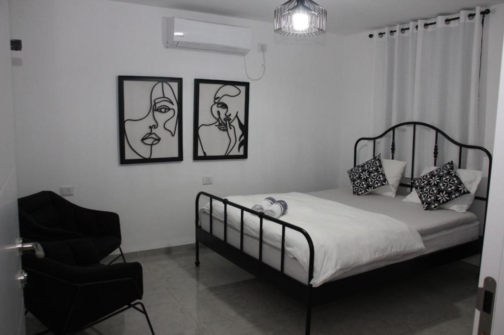Habitación en blanco y negro con cama y silla en וילה במעיין, en Gid‘ona