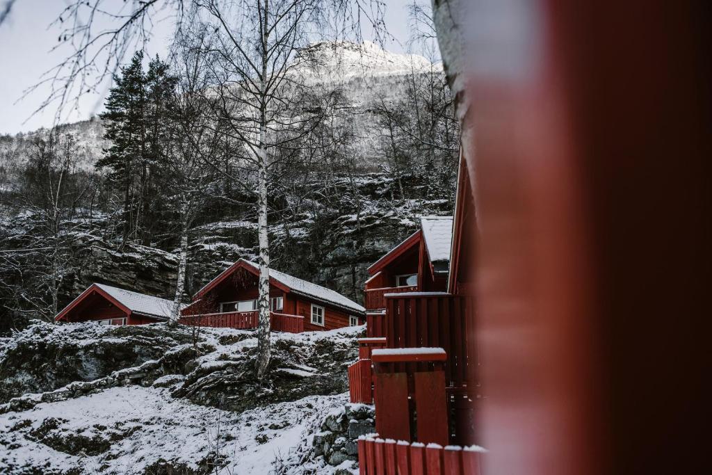 a group of red cabins with snow on the ground at Vinje Camping in Geiranger