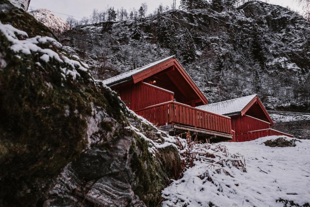 a red cabin with snow on the side of a mountain at Vinje Camping in Geiranger