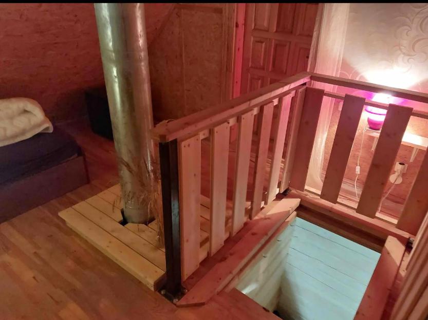 Una escalera de madera en una habitación con cama en Ramus Ūkis 
