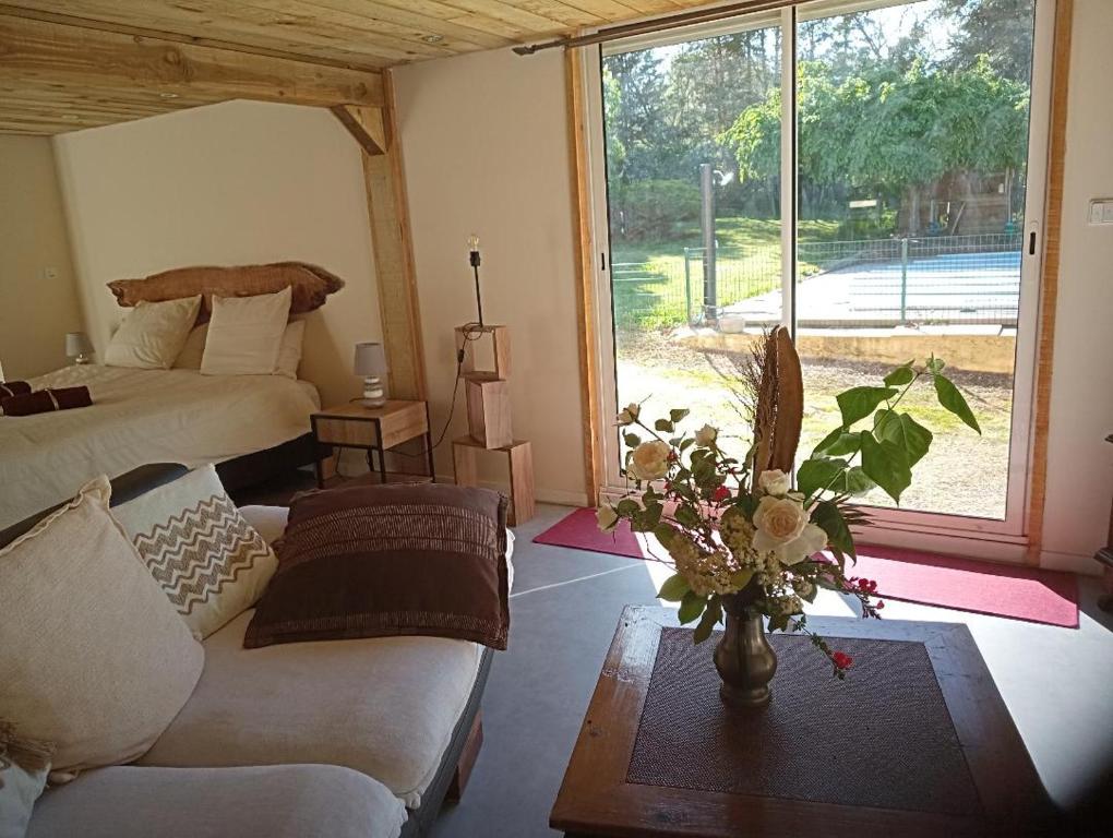 Sala de estar con cama, sofá y mesa en La Canette de Phil - Chambre d'hôtes, Indépendante - Vue sur piscine, en Samatan