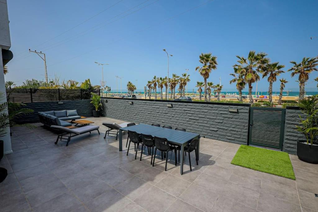 un patio con tavoli, sedie e spiaggia di וילת פאר בקו ראשון לים a Ashdod