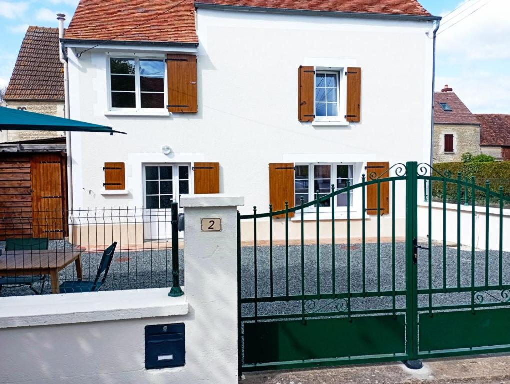 une maison blanche avec une clôture verte dans l'établissement gite du puits, à Bernières-dʼAilly