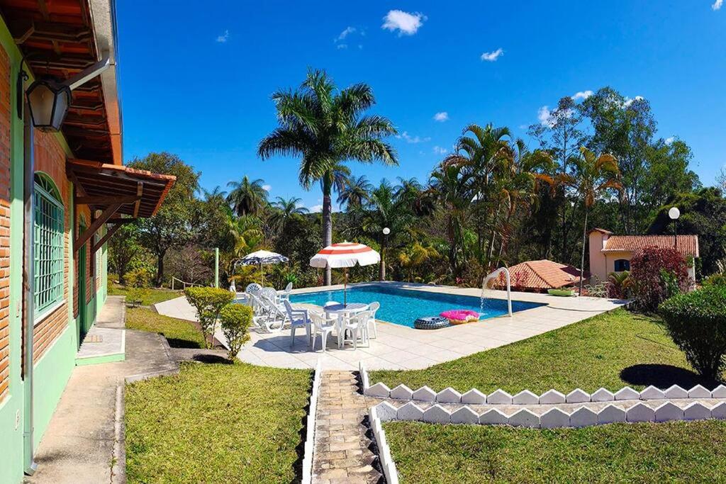 einen Hinterhof mit einem Pool und einem Haus in der Unterkunft Cantinho da Siriema - Sua fuga de diversão na Natureza a 55km de BH 