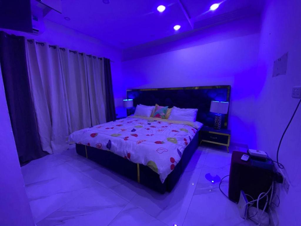 a bedroom with a large bed with purple lighting at IRISH Apartment in Kasoa