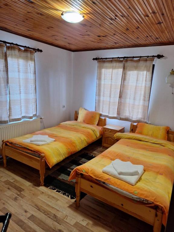 two beds in a room with wooden ceilings and windows at Sunny Guest House in Boykovtsi