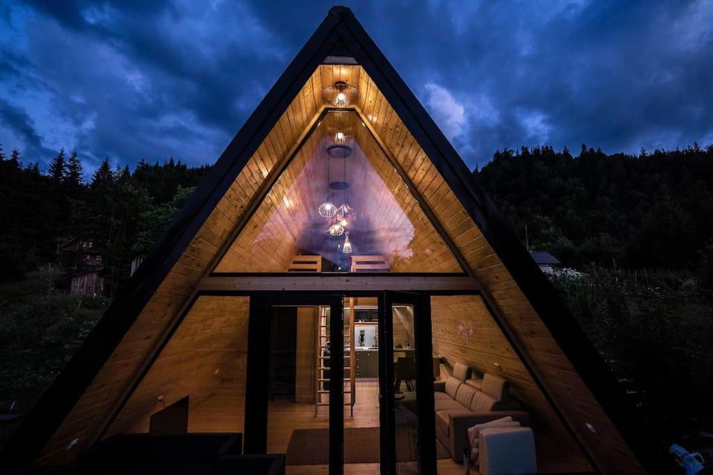 a small house with a triangular roof with a living room at Casuta Carmen A Frame in Colibiţa