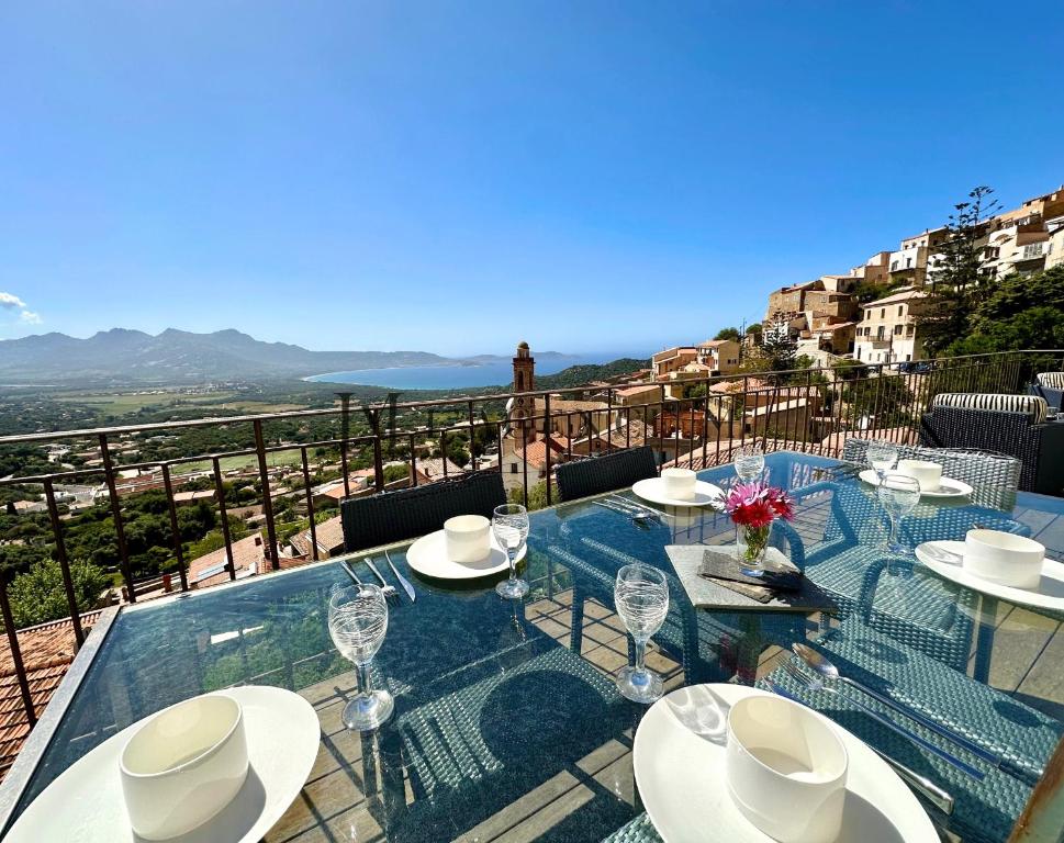 une table avec des chaises et des verres à vin sur un balcon dans l'établissement Maison golf de calvi couchers de soleil vue mer LUMIO, à Lumio