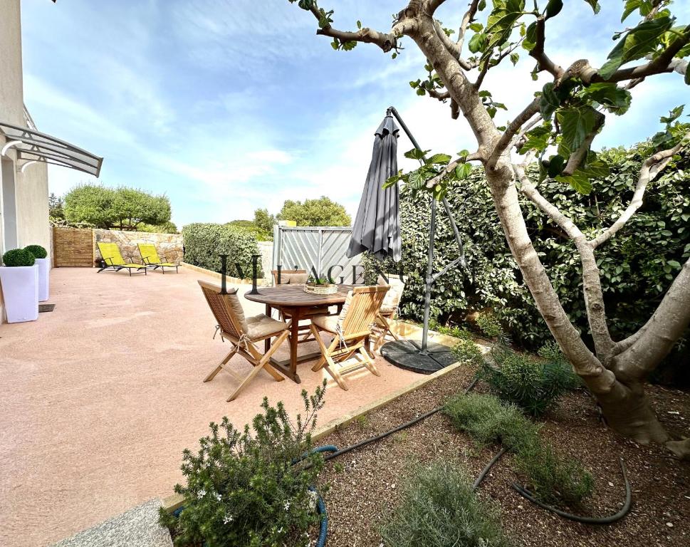 a patio with a table and an umbrella and chairs at Appartement Saint-Antoine, paisible in Calvi