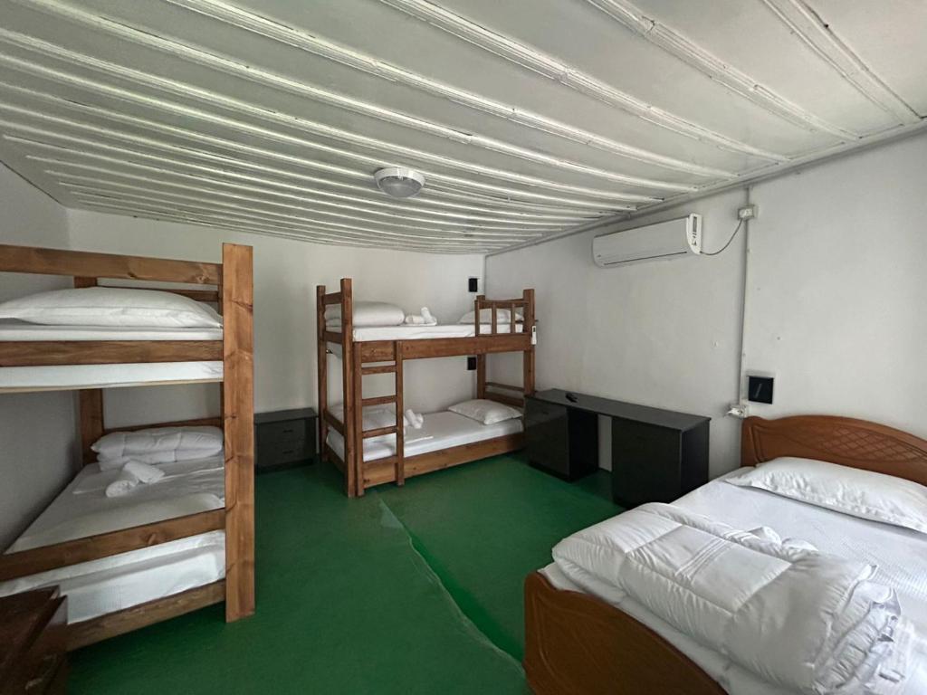 a room with two bunk beds and a green floor at The Bridge Hostel in Berat