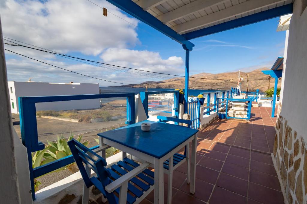 una mesa azul y sillas en un porche con vistas al desierto en Ventanas de Lanzarote, en Playa Quemada