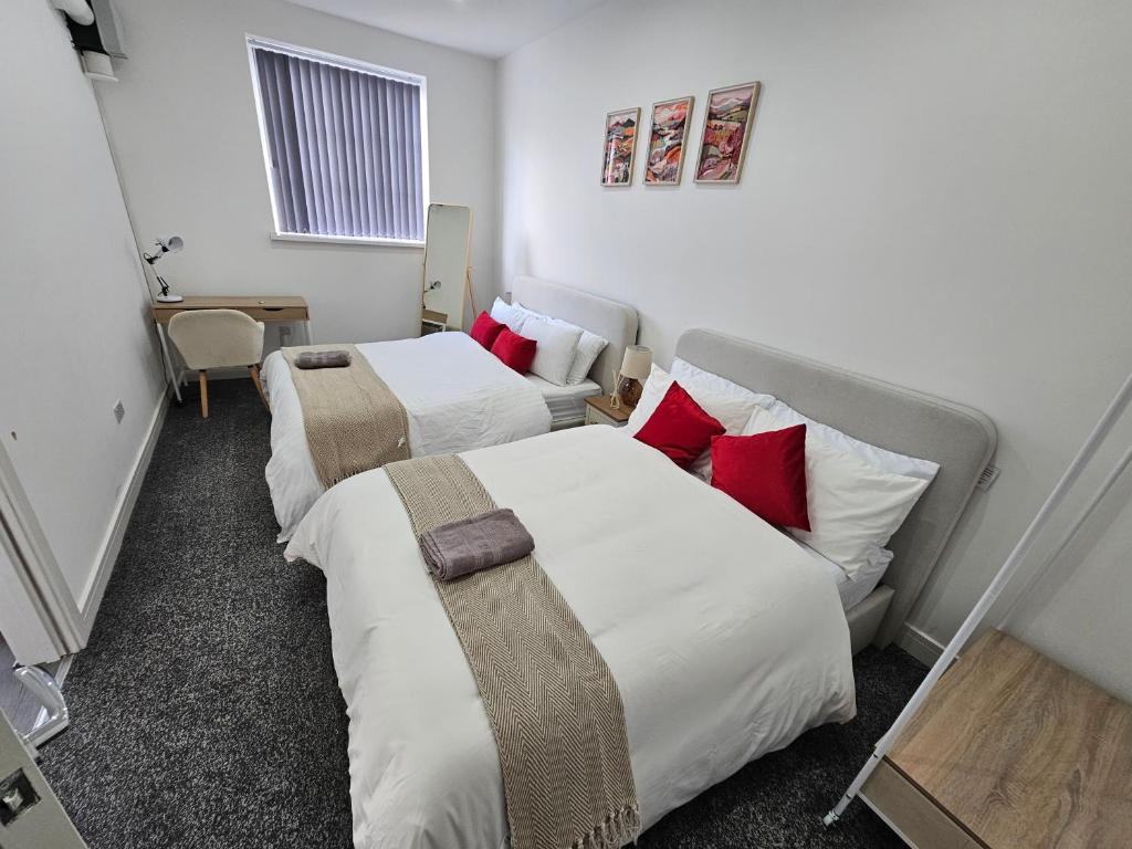 duas camas num quarto de hotel com almofadas vermelhas em Stylish 1 bed Apartment in Newly Refurbished Building w/ Parking & Wi-Fi em Birmingham