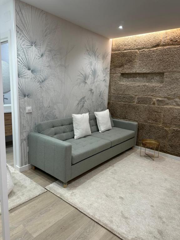 un sofá en una sala de estar con una pared de ladrillo en Lar do Arco 1, en Pontevedra