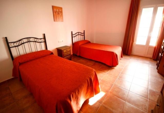 a hotel room with two beds and a window at Casa Rural El Limonero in Los Naveros