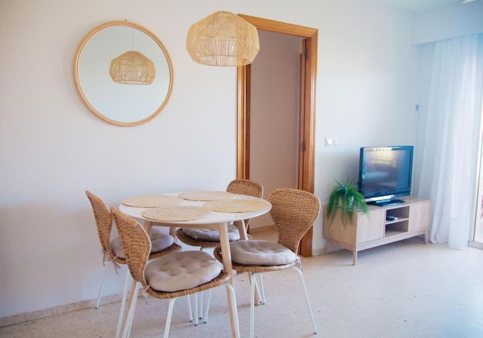 comedor con mesa, sillas y espejo en Apartamento con piscina en Playa de Gandía en Playa de Gandia