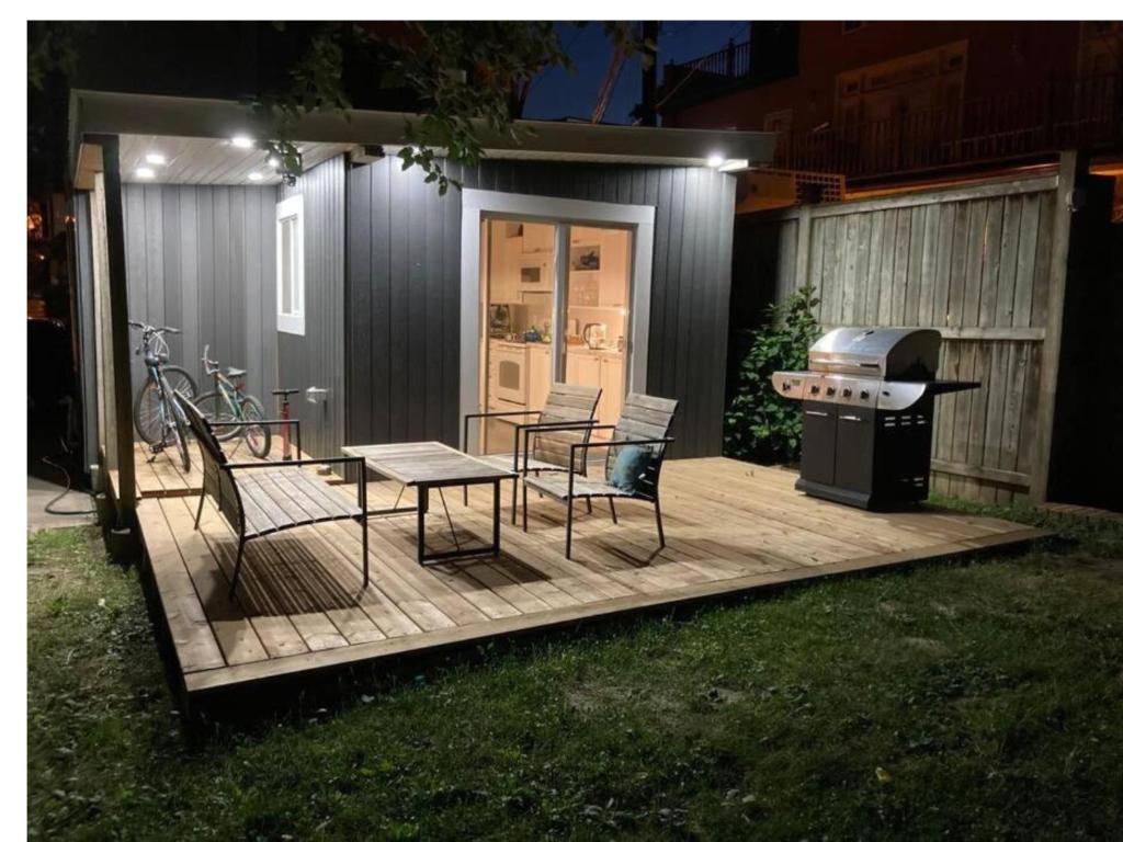 a backyard deck with a grill and chairs and a table at Lovely Leslieville, exploring nature in the city in Toronto