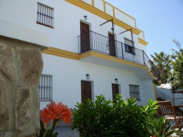 a white building with a balcony and some plants at Casa Rural El Limonero in Los Naveros