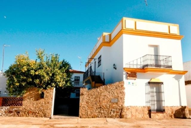 un bâtiment blanc avec un arbre devant lui dans l'établissement Casa Rural El Limonero, à Los Naveros