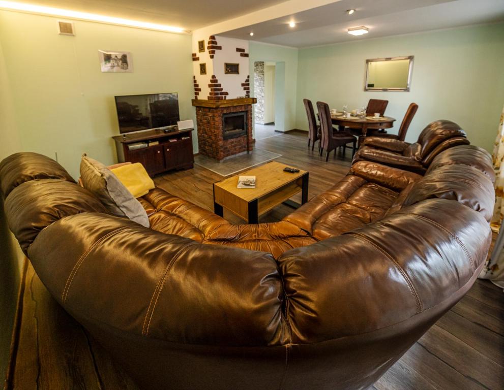 sala de estar con sofá de cuero marrón y mesa en Domek przy Rynku, en Głogówek