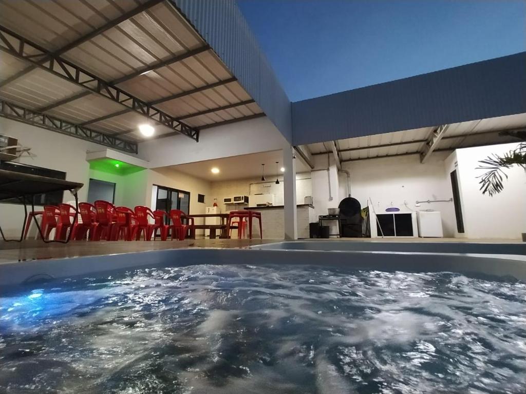 una piscina en medio de una habitación con sillas rojas en Temporada de Hidro, piscina e casa privativas - Estadia memorável ou Evento, e pode check-in flexível 15h à madrugada, en Sorriso