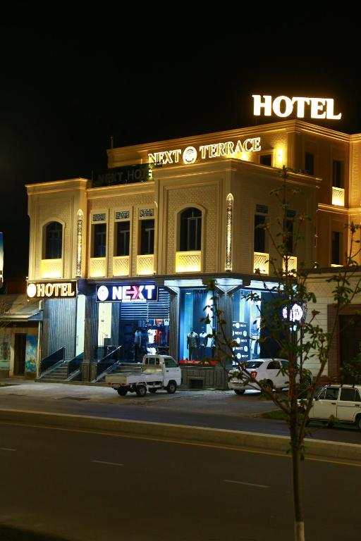 un hôtel avec des voitures garées devant lui la nuit dans l'établissement Next Hotel Samarkand, à Samarcande