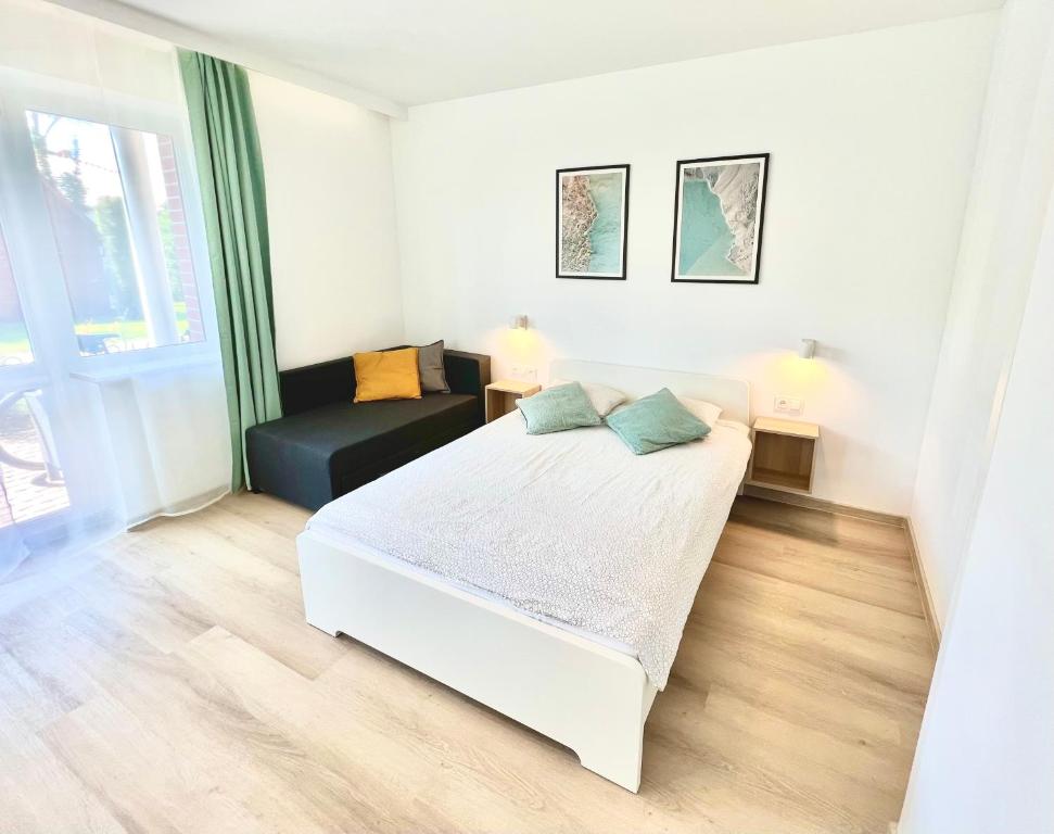 a white bedroom with a bed and a couch at B&B Fajne Miejsce in Łeba