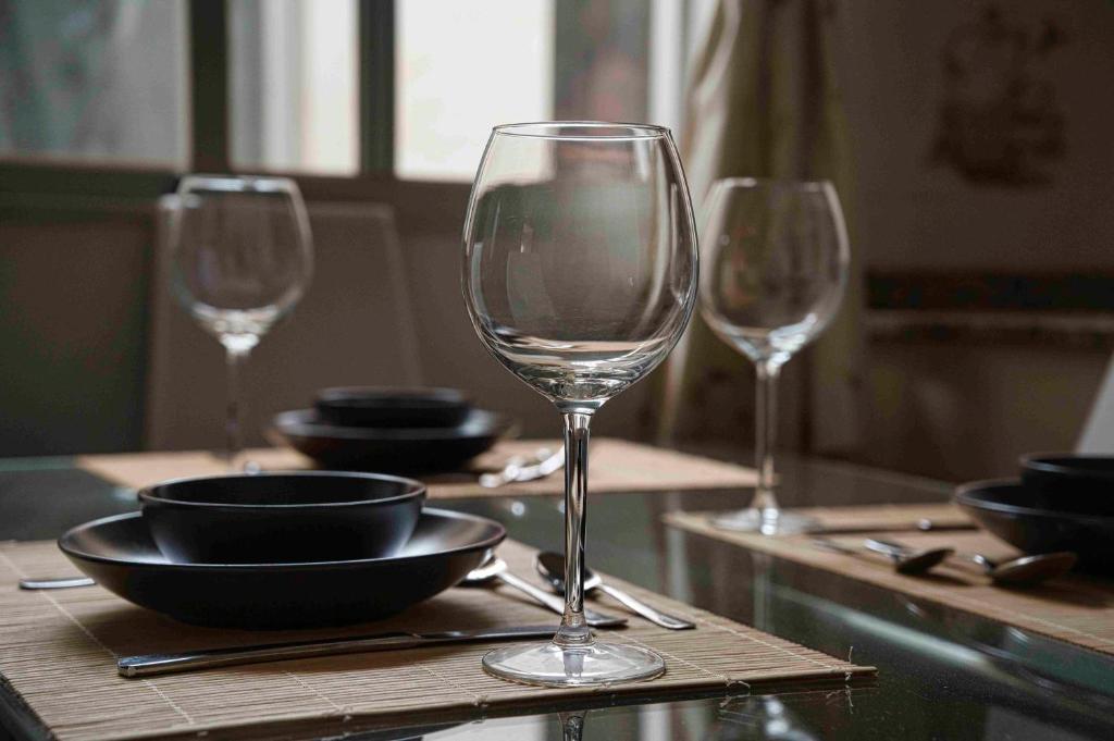 tre bicchieri da vino seduti su un tavolo con piatti e ciotole di Appartement Sunshine a Los Alcázares