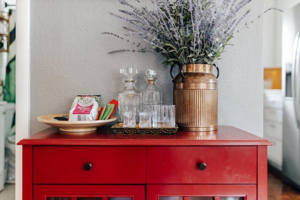 a red cabinet with a vase of flowers on it at 2BR 3BDs Historical TREE HOUSE on UT Campus in Austin